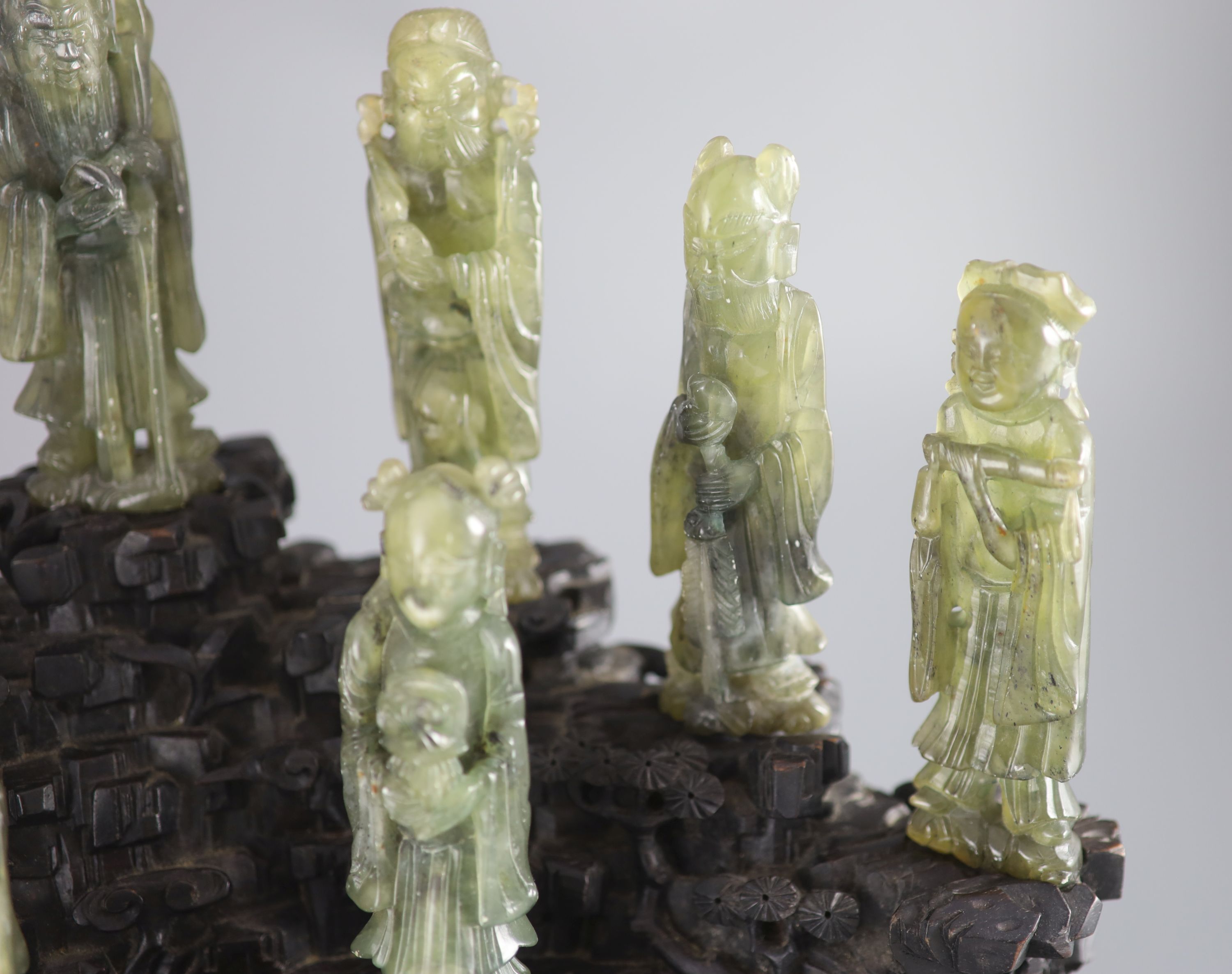 A set of nine Chinese soapstone figures of the Eight Immortals and Shou Lao, on a good zitan two piece rockwork stand, late Qing dyna